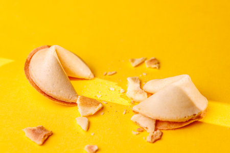 Traditional golden fortune cookies on a bright yellow surface. This iconic snack is perfect for...