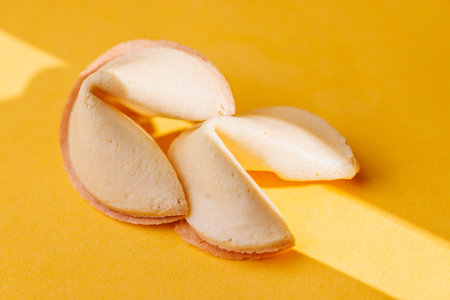 Traditional fortune cookies on a bright yellow surface. A great visual for representing luck and...