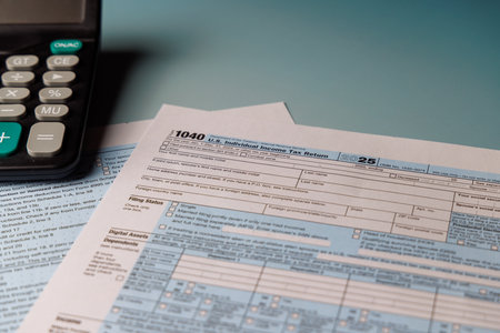 A desk shows the word TAX on Form 1040 with tools. Perfect for illustrating IRS tax returns and payment deadlines with natural sunlight in the office.の写真素材