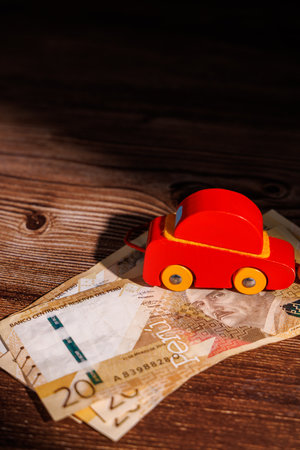 Car market problems in Peru with a toy vehicle on cash. High quality image for representing leasing crisis, debt and automotive investment themes now.の写真素材