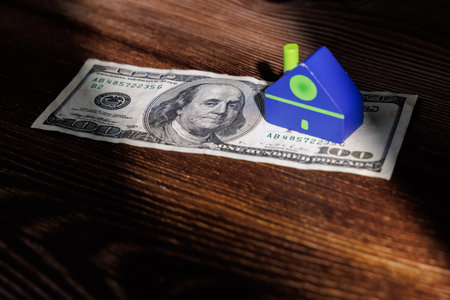 American real estate market challenges with a toy house on dollar bills. Ideal for representing...