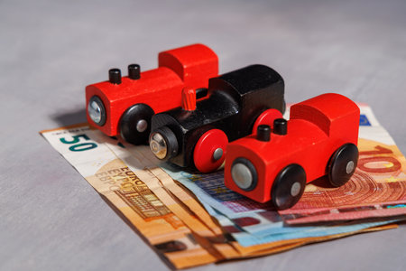 Toy train on money notes. High quality visual for representing the high price of moving, transport...