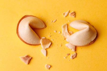 Crunchy fortune cookies on an intense yellow surface. The cinematic lighting emphasizes the detail...