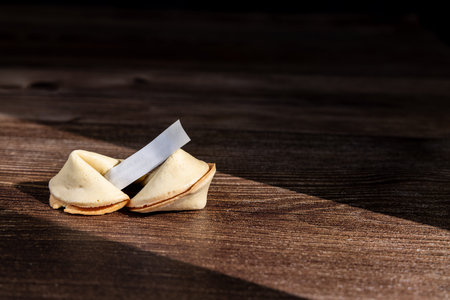Classic Asian fortune cookies on a dark wood surface. These iconic snacks are perfect for...