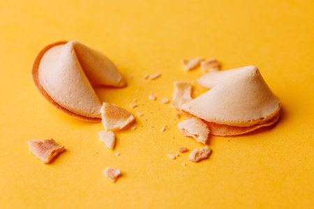 Golden crispy fortune cookies on an intense yellow surface. Ideal for representing prosperity and...