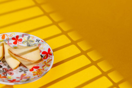 Golden fortune cookies on a decorative plate with flowers over an intense yellow surface. Ideal for future, destiny and traditional oriental ads!!の写真素材