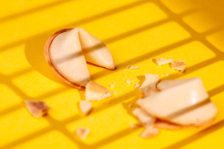 Golden crispy fortune cookies on an intense yellow surface. This iconic snack is perfect for...