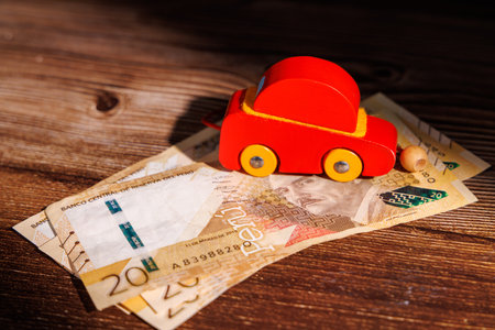 Wooden toy car on 20 Soles bills. Ideal for representing the car price crisis, high loan costs and vehicle affordability challenges in Peru today.の写真素材