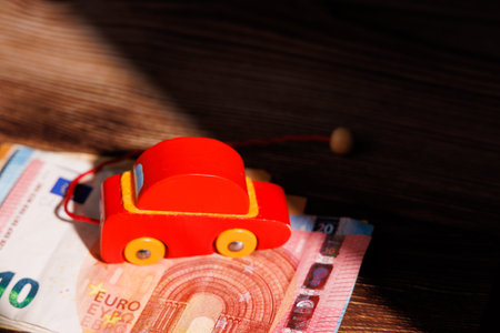 European car affordability crisis with a wooden toy car on Euro bills. Ideal for representing banking loans, auto finance and expensive rentals.の写真素材