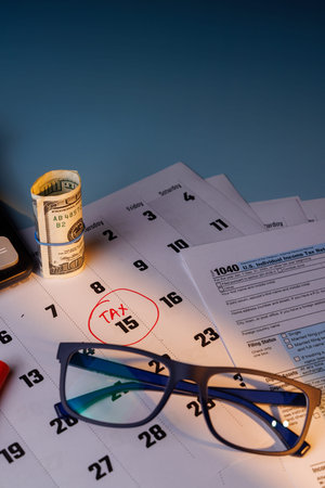 Financial tax season concept with color Form 1040 and a 100 dollar bill. Sunny workspace with blue...