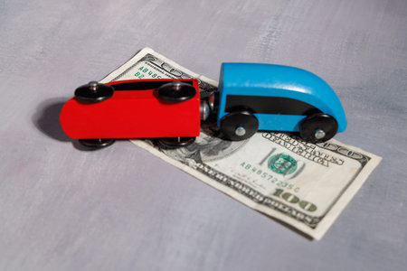 Wooden toy train off tracks on dollar bills. Ideal for representing business failure, currency instability and economic recession in the United States.の写真素材
