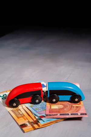 Wooden toy train over cash. Perfect for illustrating expensive commuting, financial barriers to travel and the growing wealth gap in transportation.の写真素材