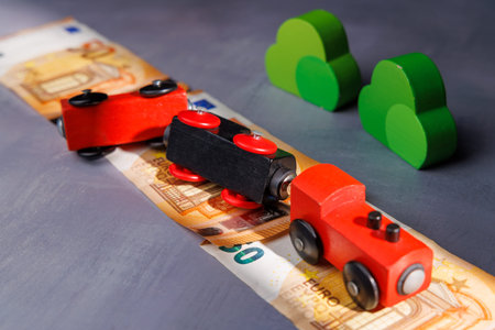 Derailed wooden train on Euro bills. Perfect for illustrating economic downturn, monetary health issues and the impact of inflation on investments.の写真素材