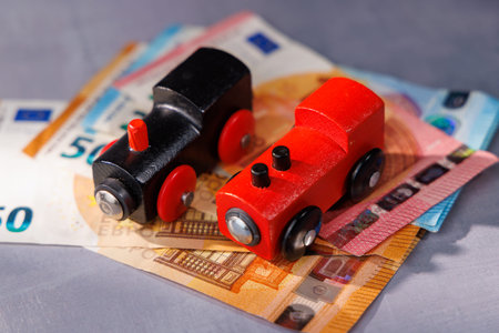Wooden toy train over money bills. Ideal for representing business risk, investment strategies and the fragile balance of global economic stability.の写真素材