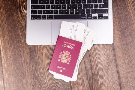 Looking down at a spanish identity document, airline boarding passes on a laptop computer keyboard.