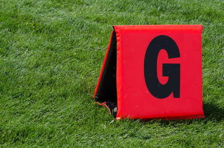 reddish orange tnet style goal line marker on green grass