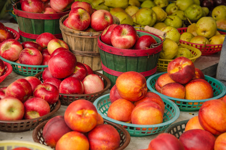 Colorful baskets full of fresh apples and peaches