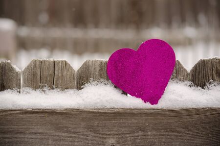 pink heart leaning against rustic fenceの写真素材