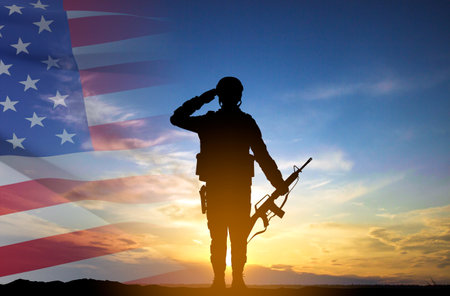 Silhouette of a soldier with USA flag against the sunset. Greeting card for Veterans Day, Memorial Day, Independence Dayの写真素材