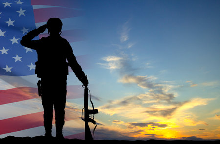 Silhouette of a soldier with USA flag against the sunset. Greeting card for Veterans Day, Memorial Day, Independence Dayの写真素材