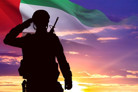 Silhouette of saluting soldier with the flag of UAE against the sunset. Armed forces of United Arab Emirates. Concept for Commemoration Day, Martyrs Day, National Dayの写真素材
