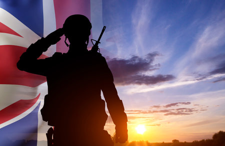 Silhouette of a soldier with United Kingdom flag against the sunset. Background for Remembrance Day....