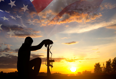 Silhouette of man kneeling down with USA flag against the sunset. Veterans Day, Memorial Day, Independence Day conceptの写真素材