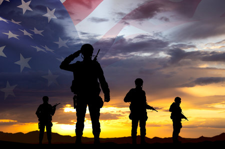 Silhouettes of a soldiers with USA flag against the sunset. Veterans Day, Memorial Day concept