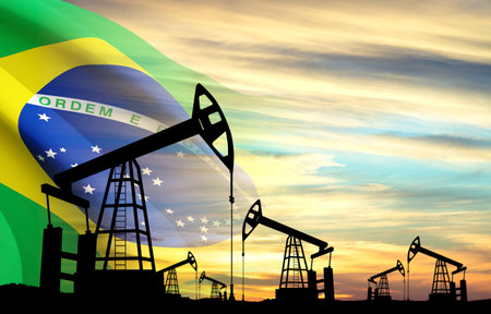 Silhouette of oil pumpjacks against the sunset sky with Brazil flag.の写真素材