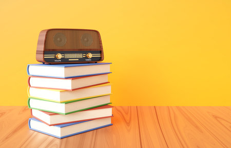 Vintage radio with books standing on a wooden desk near orange wallの写真素材