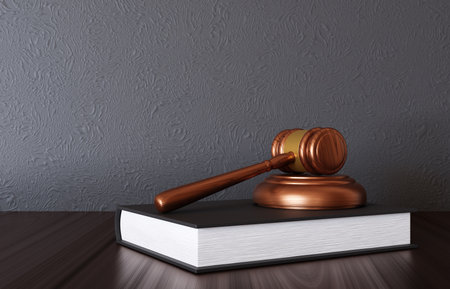 Wooden judge gavel with book on the desk near gray wallの写真素材