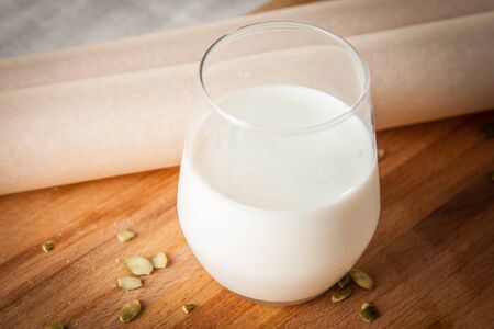 Gloss of milk on wooden cutting board with seeds and baking paperの写真素材