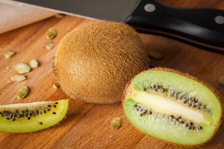Closeup kiwi cut by half on wooden cutting board with knifeの写真素材