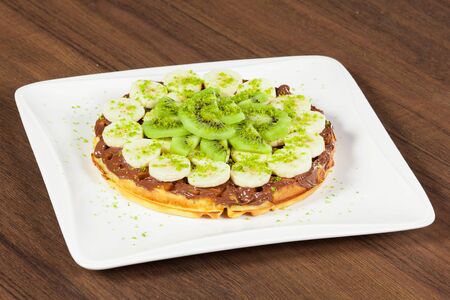 Waffle topped with bananas, kiwis and chocolate.の写真素材