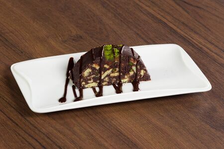 Chocolate cake in white plate on wooden table.の写真素材