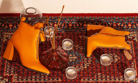 A set of women's shoes shot in the studio against the background of the carpet in retro style with candles.の写真素材
