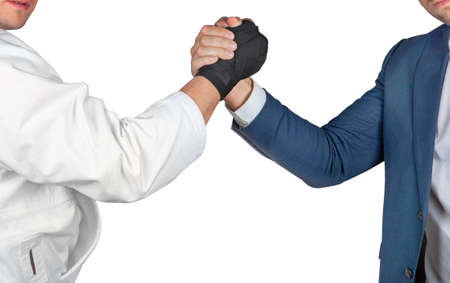 Businessman in suit handshake with judoka boxing gloves in white kimono isolated.の写真素材