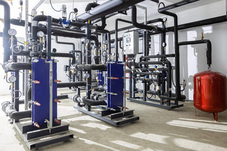 Industrial basement with heating pipes, pressure gauges, valves and heat exchangers.の写真素材