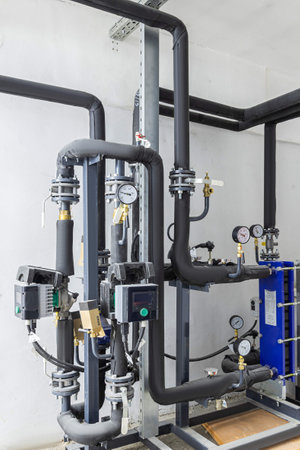 Industrial basement with heating pipes, pressure gauges, valves and heat exchangers.の写真素材