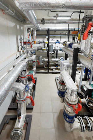 Industrial basement with heating pipes, pressure gauges, valves and heat exchangers.の写真素材
