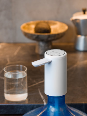 A transparent bottle filled with refreshing water is resting on a countertop adjacent to a clear glass of water filled to the brimの写真素材