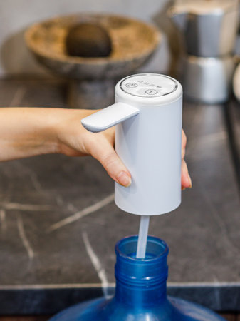 A person is in the process of pouring some water into a blue bottle that features a straw for easy sipping or drinking purposesの写真素材
