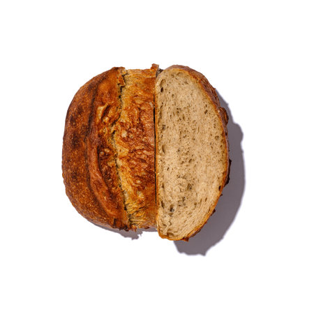 A freshly baked loaf of bread has been neatly cut in half, displaying its soft interior against a...