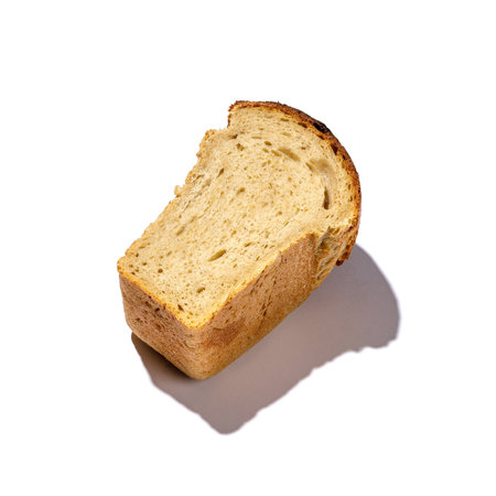 A freshly baked loaf of bread, with a sizeable bite taken out of it, is placed on a clean white...
