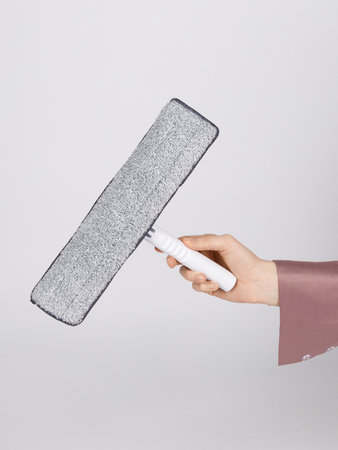 A person is currently holding a mop firmly in their hand, preparing to clean and tidy up their...