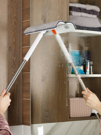 A person is diligently cleaning a bathroom mirror using a mop in order to ensure that it is spotless and streakfree for better visibilityの写真素材