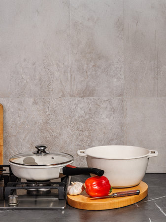 A pot is placed on the stove, right beside a vibrant pepper and some aromatic garlic, creating an...