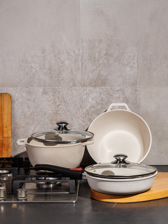 A collection of white pots and pans featuring stylish glass lids neatly arranged on a stove top, ready for cooking delicious mealsの写真素材