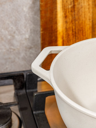 A pristine white pot is positioned atop a stove, while a rustic wooden cutting board can be seen in the background of the kitchen sceneの写真素材