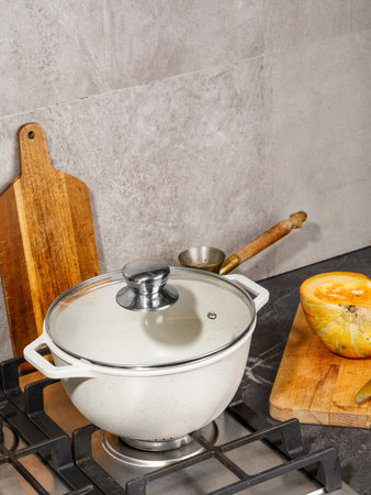 There is a pot placed on top of a stove, which is conveniently positioned right next to a cutting board for easy preparation tasksの写真素材